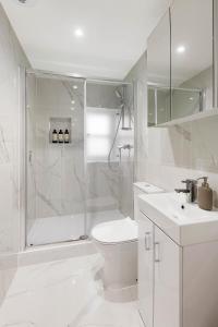a white bathroom with a shower and a toilet and a sink at Luxury Chelsea Flat in London