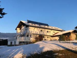 un bâtiment avec des panneaux solaires dans la neige dans l'établissement Hotel "Haus am Berg", à Rinchnach