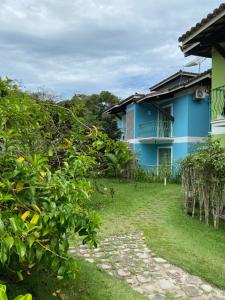 a blue house with a yard in front of it at Flores da Aldeia in Arraial d'Ajuda