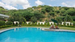 una piscina con 2 sillas y una sombrilla en Amar Bagh Resort, en Pushkar