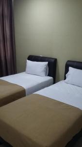 two beds sitting next to each other in a room at Stephanie Hotel in Teluk Intan
