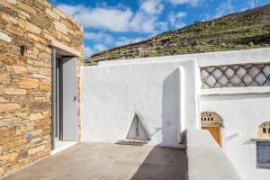 een wit huis met een stenen muur en een trap bij Tinos Pigeon House by TinosHost in Tzádhos