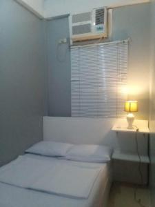 een witte slaapkamer met een bed, een raam en een lamp bij Kendall place Apartments in Cagayan de Oro