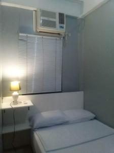 een slaapkamer met een bed en een raam met airconditioning bij Kendall place Apartments in Cagayan de Oro