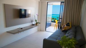 a living room with a blue couch and a television at APARTAMENTO ALTO LUXO A 4MIn DO MAR TIME in Maceió