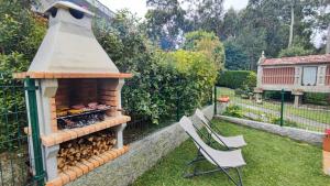 un patio trasero con horno de leña y 2 sillas en Casa Jardin Vigo, en Vigo