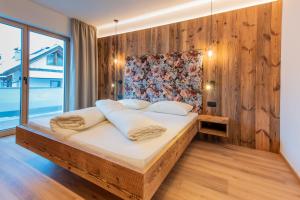 1 dormitorio con 1 cama con pared de madera en Apartments Ciasa Costisela, en San Vigilio Di Marebbe