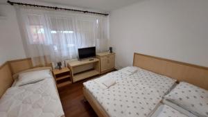 1 dormitorio con 2 camas y escritorio con TV en Fáraó vendégház, en Zalaegerszeg