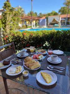 a table with plates of breakfast foods on it at Pousada Hippopotamus Jeri in Jericoacoara
