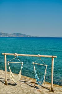 two hammocks hanging on a wooden rail near the water at Paradisso Beach Villas in Amoudi