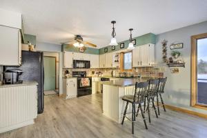 a large kitchen with white cabinets and bar stools at Lake Nokomis Escape with Dock and Beach Access in Tomahawk