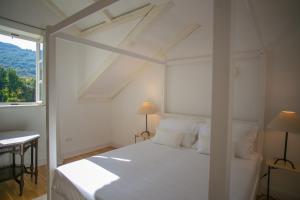 a white bedroom with a white bed and a window at Revelin Hvar in Stari Grad