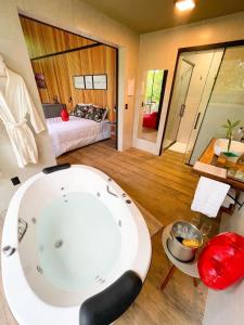 a bathroom with a bath tub and a bedroom at Pousada Sitio Raizes in Siderópolis