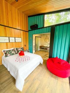 a bedroom with a bed and a red ottoman at Pousada Sitio Raizes in Siderópolis