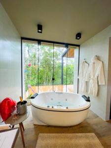 a large bath tub in a room with a large window at Pousada Sitio Raizes in Siderópolis