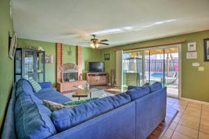 a living room with a blue couch and a tv at Breeze By the Pool Retreat with Game Room! in Chula Vista