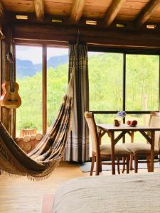 a hammock in a room with a table and a large window at Cabana com vista para o canyon in Praia Grande