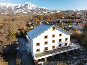 uma vista aérea de uma casa branca com montanhas ao fundo em Hôtel Logis La Crémaillère em Saint-Bonnet-en-Champsaur