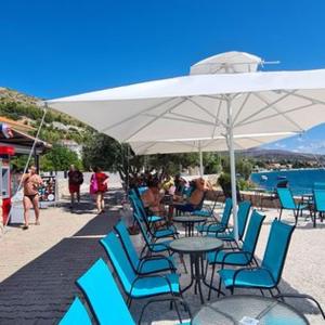 a table and chairs under an umbrella on the beach at Apartmani Gizela in Trogir