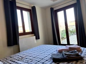 una camera con un letto con due finestre e asciugamani di Appartement calme au coeur du jardin a Violaines