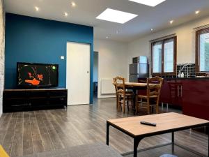 un salon avec une télévision et une salle à manger dans l'établissement Appartement calme au coeur du jardin, à Violaines