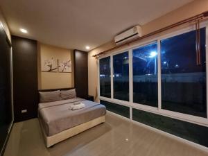 a bedroom with a bed and a large window at Tinker Bell Pool Villa in Jomtien Beach