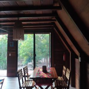 drewniany stół i krzesła w pokoju z dużym oknem w obiekcie Eco Aldea kinich Ahau w mieście Xpujil