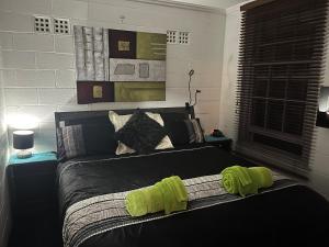 ein Schlafzimmer mit einem Bett mit grünen Handtüchern darauf in der Unterkunft The downstairs delight 2brm , 6+ guests & dogs ok in Lake Munmorah