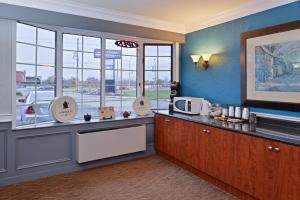 a kitchen with a counter with a microwave and windows at Canadas Best Value Inn St. Catharines in St. Catharines