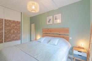 a bedroom with a large white bed and a table at Résidence du Haurat in Gujan-Mestras