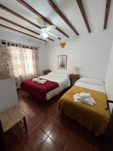 a bedroom with two beds and a ceiling fan at Casa Jara in Jimera de Líbar