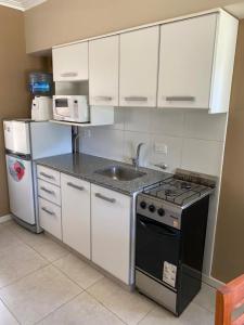 a kitchen with white cabinets and a stove and a sink at Icalma De La Sierra in Tandil
