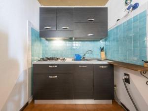 a kitchen with black cabinets and blue tiles at VILLA CLAUDIO e LUNETTA in Villasimius