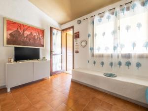 a living room with a flat screen tv and two windows at VILLA CLAUDIO e LUNETTA in Villasimius