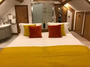 a large bed with yellow and orange pillows in a bathroom at Exclusive Use of A Barn in Arundel