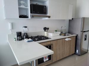 a white kitchen with a stove and a refrigerator at RESERVA DEL MAR - Playa Salguero - By INMOBILIARIA VS in Santa Marta