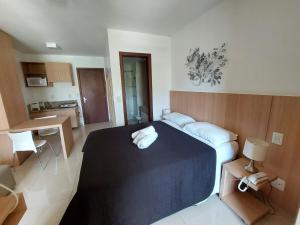 a bedroom with a large bed and a kitchen at The Sun Flat Beira Lago in Brasilia