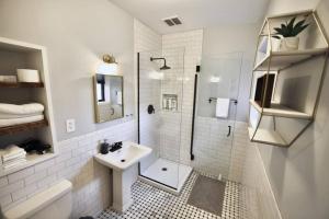 La salle de bains blanche est pourvue d'un lavabo et d'une douche. dans l'établissement HostWise Stays - The Ohioan - Beautiful Brick Apt, Minutes to Downtown!, à Pittsburgh
