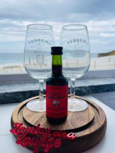 two wine glasses and a bottle of wine on a wooden tray at Zambujeira Lounge in Zambujeira do Mar