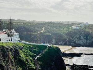 a view of a beach with a building on a cliff at Zambujeira Lounge in Zambujeira do Mar