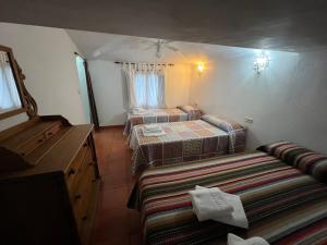 2 Betten in einem kleinen Zimmer mit Fenster in der Unterkunft Casa Lirios in Jimera de Líbar