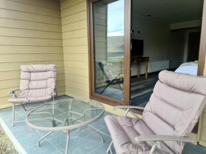 eine Terrasse mit 2 Stühlen und einem Glastisch in der Unterkunft Hotel HORSTMEYER in Cochrane