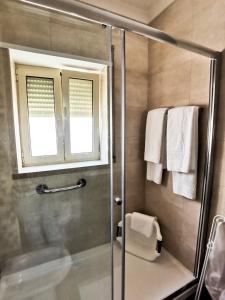 a bathroom with a shower with a glass door at Casas dos Avós in Nazaré