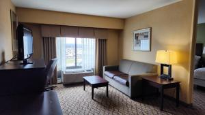 a living room with a couch and a television in a hotel room at Wingate by Wyndham Kittanning in Kittanning