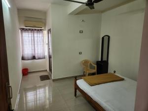 - une chambre avec un lit et une chaise dans l'établissement Raja Rani Mahal Ac-Rooms, à Tiruvannāmalai