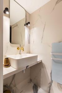 Baño blanco con lavabo y espejo en Cosy Appart - 3BR6P Jardin du Luxembourg Odeon en París