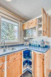 a kitchen with wooden cabinets and a sink and a window at Boho Retreat w/King Bed on Bow River Pathway in Calgary