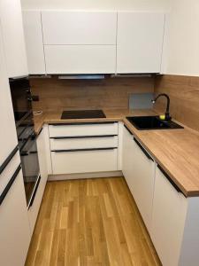 a kitchen with white cabinets and a wooden floor at Apartman Holesovice,balkon,garaz in Prague