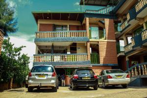 twee auto's geparkeerd voor een gebouw bij Heartland hotel in Kigali