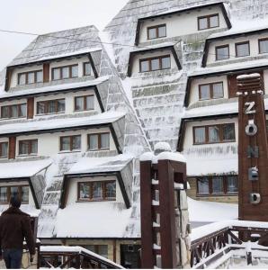 コパオニクにあるMountain Lux Zonedの雪に覆われた建物の前を歩く男性